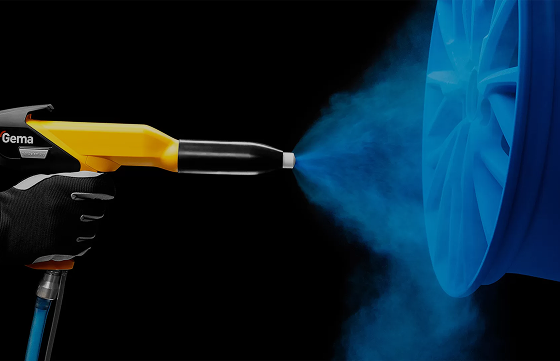 Powder coating spray gun applying blue powder to a blue wheel rim against a black background
