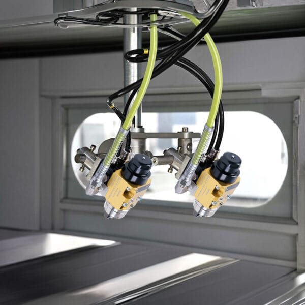 Two yellow automatic spray guns with hoses mounted inside a spray booth